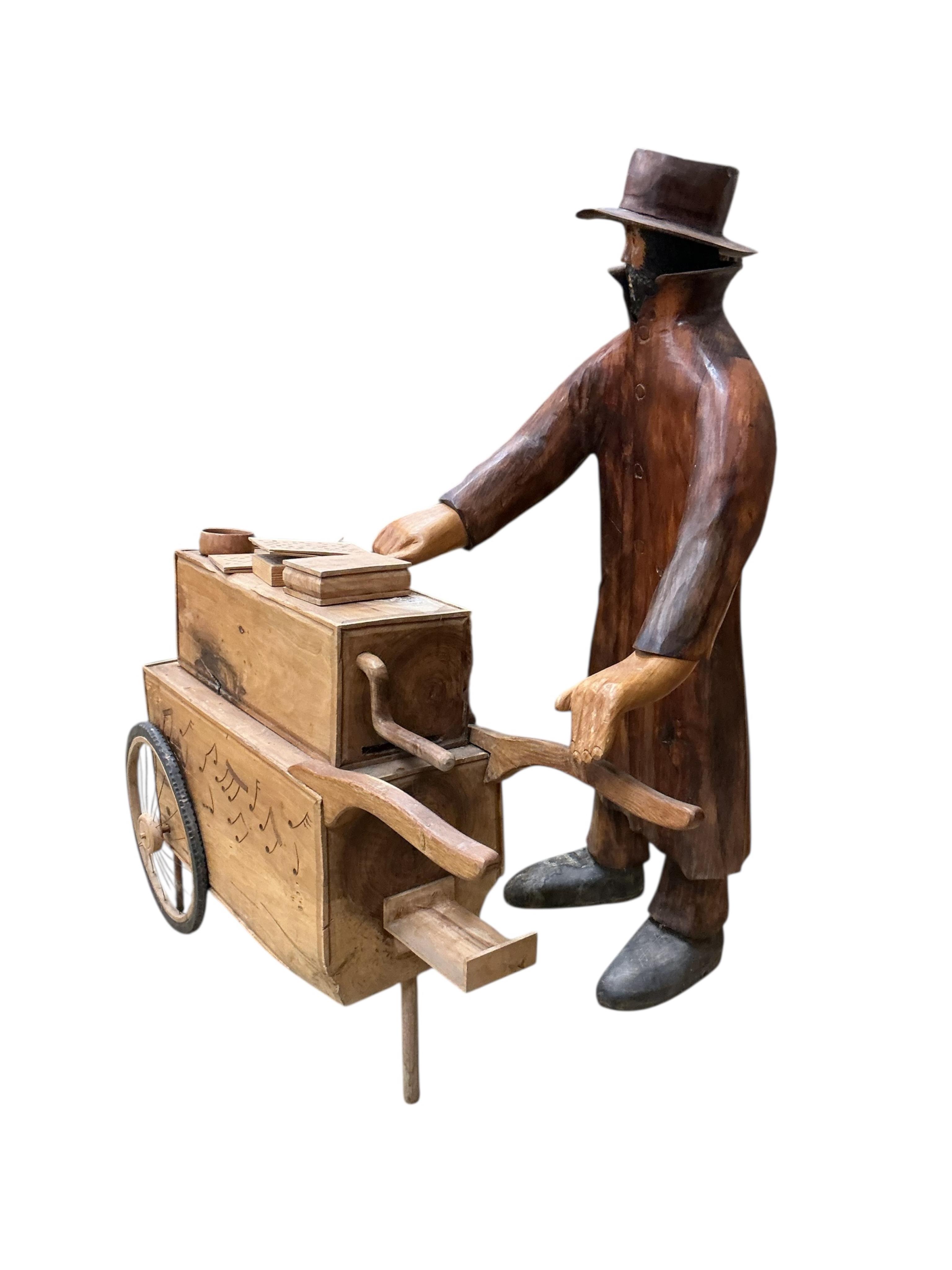 Pierre Decorse (b.1953), a carved wooden sculpture of a man playing the hurdy-gurdy